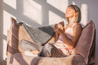 Woman relaxing in soft sunlight, wrapped in a cozy blanket—embracing calm during perimenopause.
