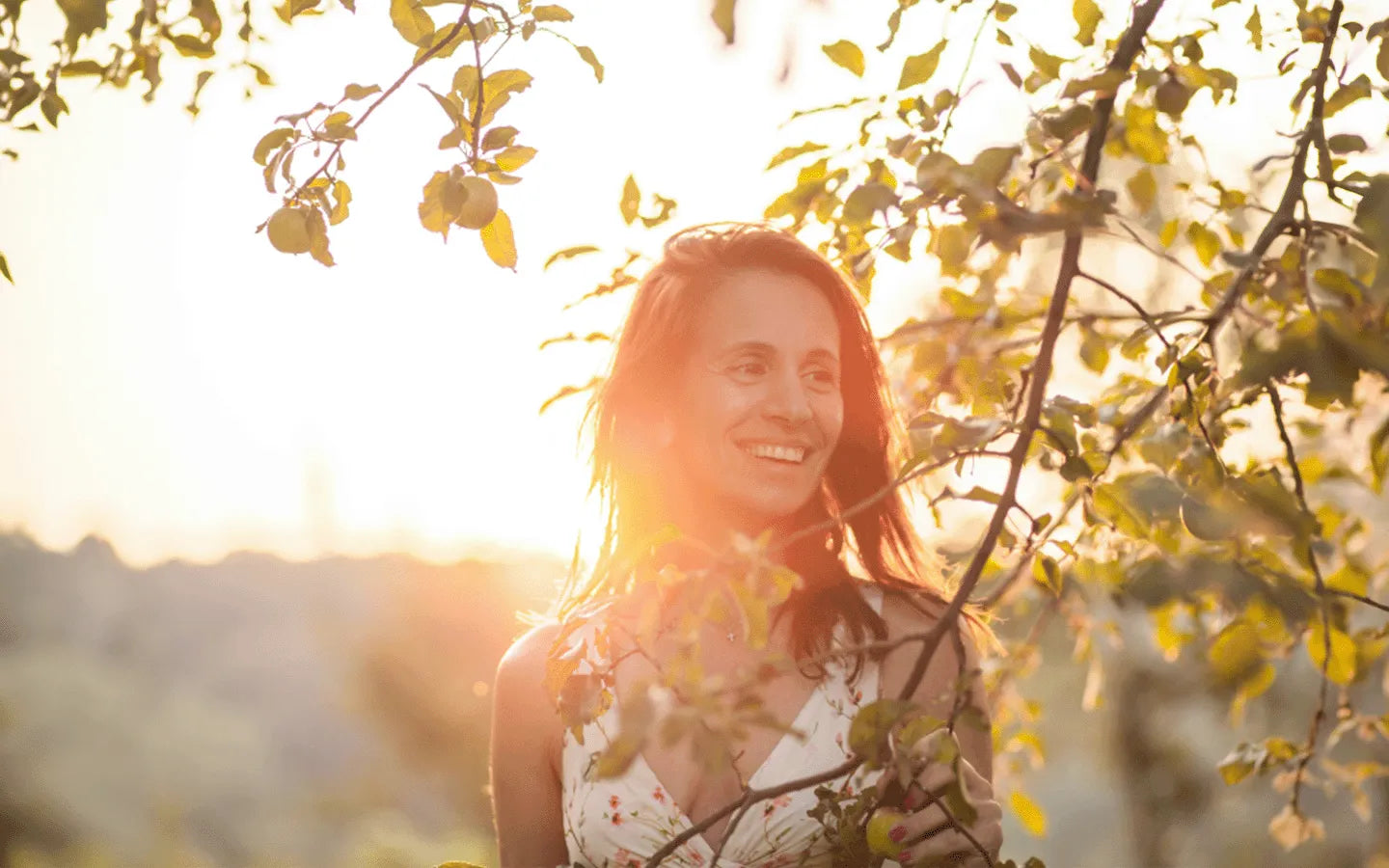 Woman smiling in sunlight, representing perimenopause journey.